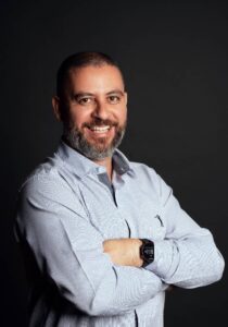 Foto de Andres Pereira em pé com braços cruzados e sorrindo